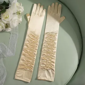Detailed close-up of long satin ruched wedding bridal gloves in elegant champagne tone.
