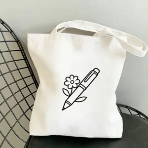 Detailansicht einer weißen Leinentasche mit Stift und Blume Linienkunst auf dem Stuhl.