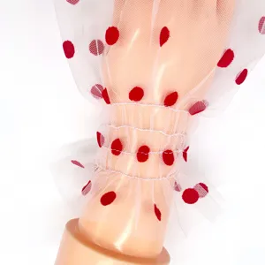Detailed view of white sheer mesh sleeve with red polka dots and ruffled smocked cuffs.