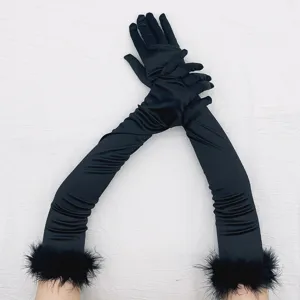 Closeup of long black satin gloves featuring fluffy faux fur trim, elegant vintage style detail.