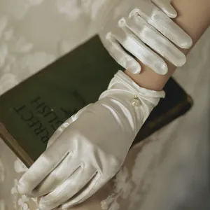 White satin bridal gloves detail featuring elegant pearl pendant decoration for weddings.