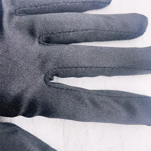 Close-up detail of black stretch satin gloves, smooth fabric texture and fine stitching.