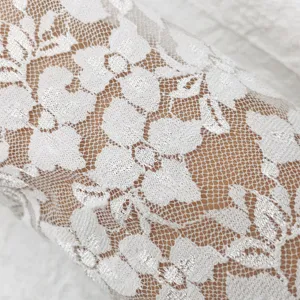 Close-up detail of elegant white floral lace gloves fabric texture showing fine mesh and patterns.