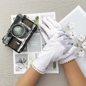 Close-up detail of white satin ceremonial gloves with elegant pearl wrist trim for events.