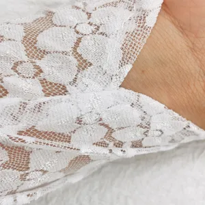 Detailed close up of white floral lace fabric texture on elegant party gloves accessory.