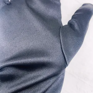 Detailaufnahme von schwarzem Satinhandschuh-Stoff mit feiner Textur und glattem Material.