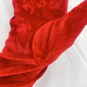 Close-up detail of winter long red velvet gloves, showing soft texture and premium fabric.