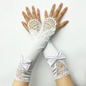 Detalle de guantes de novia de encaje blanco con delicado bordado floral y lazo de satén.