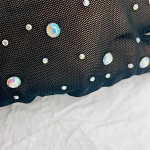 Gros plan de gants en dentelle résille noire ornés de strass irisés scintillants et brillants.