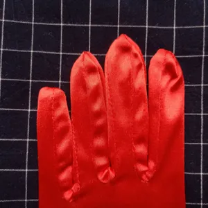 Vue détaillée de gant en satin rouge, texture de tissu lisse et coutures soignées.