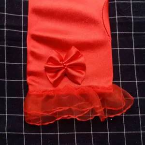 Détail du gant de mariée rouge mettant en valeur le nœud en satin et la manchette en dentelle.