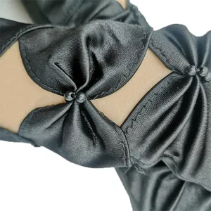 Black satin hollow-out evening gloves close-up showing delicate bead and pleated texture details.