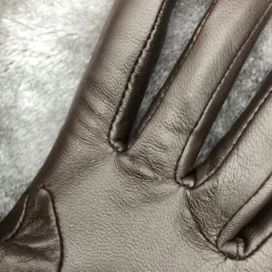 Close-up detail of brown sheepskin leather winter gloves showing exquisite stitching and texture.