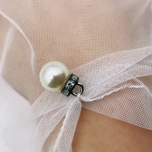 Close-up of sheer mesh lace bridal glove with a delicate pearl and rhinestone pendant charm.