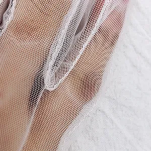 Close-up detail of white mesh lace fabric, lightweight summer bridal glove accessory.