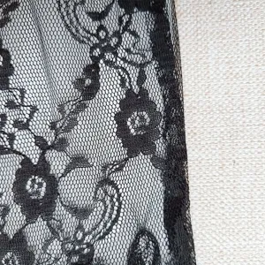 Detailed close-up view of black elastic lace fabric featuring delicate floral mesh trim design.
