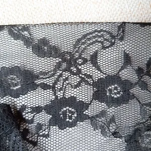 Black elastic lace fabric close up, delicate floral mesh design for summer gloves acc.