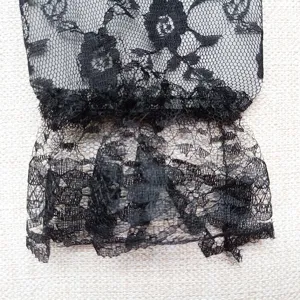 Detailed shot of black lace glove with exquisite floral mesh pattern and elegant cuff edge.