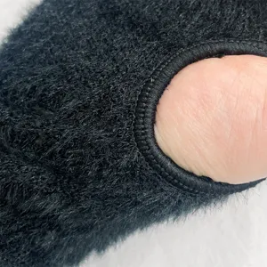 Black fuzzy knit glove detail close-up showing soft fleece texture and precise finger opening edge.