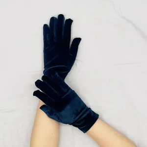 Close-up detail of dark blue velvet gloves showing soft texture and fine stitching work.