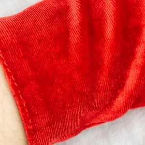Close-up view of red velvet gloves detail, showing soft texture and fine stitching.