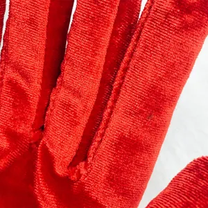 Close up view of red stretch velvet glove fabric, showing soft texture and fine stitching detail.