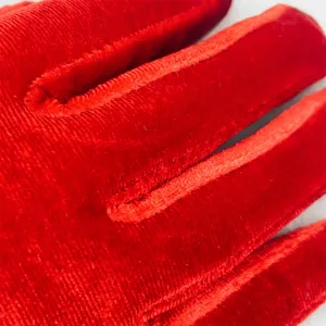Close-up detail of red velvet stretch gloves, showing soft and fine fabric texture for winter.