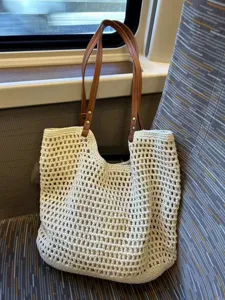 Details of the beige crochet woven tote bag featuring brown leather shoulder straps and spacious capacity.