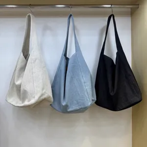 Slouchy tote bag detail showing three colors hanging neatly in a clean wardrobe display setup.