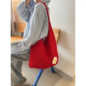 Crochet shoulder bag detail shot showcasing red knit texture and cute flower applique accent.