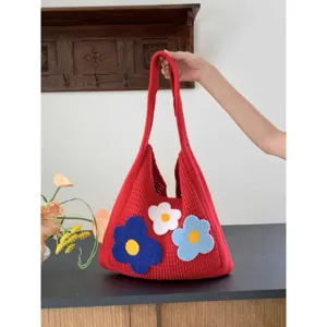 Close up detail of red knit shoulder bag with cute plush floral appliques, casual style.