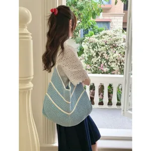 Detailed lifestyle scene of a stylish blue and white striped knitted shoulder tote bag.