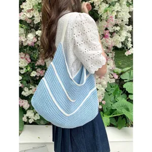 Detailed view of the light blue crochet knit shoulder tote bag with white stripes outdoors.