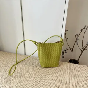 Green woven leather bucket bag detail showing intricate intrecciato pattern and knot strap.