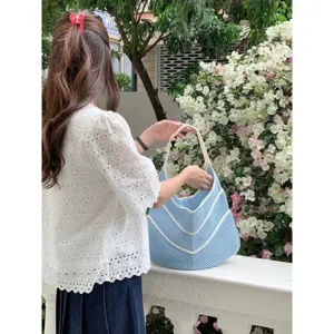 Detail view of a stylish blue and white striped crochet knit tote bag for summer beach use.