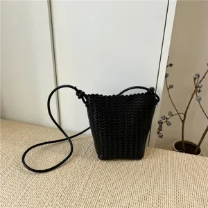Black woven leather bucket bag detail showing intricate craftsmanship and stylish knotted strap design.