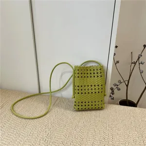 Detailed view of the green woven mini phone bag showcasing exquisite hollow pattern and strap.