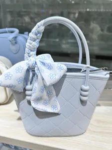 Light blue detail view of quilted handbag featuring a floral scarf wrapped handle and beads.
