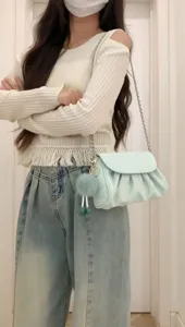 Detail shot of the light blue pleated cloud shoulder bag with chain strap and fluffy pom-pom.