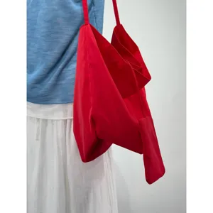 Dettaglio di una borsa a tracolla morbida rosso vivo, stile casual per uso quotidiano e lavoro.