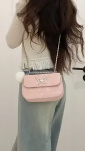 Pink patent leather chain shoulder bag with silver butterfly clasp detail worn on back view