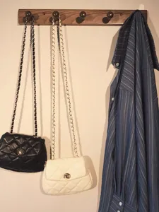 Detail view of quilted chain shoulder bags hanging on a wall hook, lifestyle display.