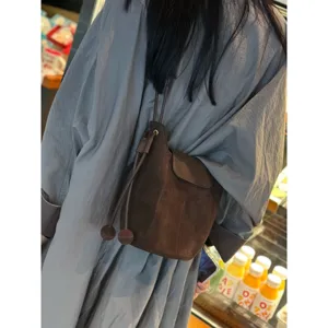 Sac seau en daim marron vue détaillée, sac bandoulière souple vintage avec cordon de serrage.