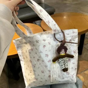 Gedetailleerde close-up van een schattige bloemen canvas tas met een leuke pop hanger.