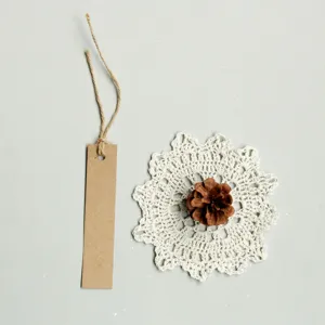 Blank kraft paper tag detail view, retro style DIY bookmark with delicate crochet lace mat and pinecone.