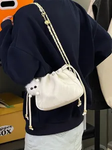 Vue détaillée du sac seau à cordon froissé blanc avec bandoulière chaîne et breloque en peluche.
