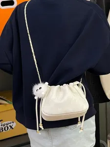 Vue détaillée d'un sac seau blanc style coréen avec bandoulière chaîne et charm duveteux.