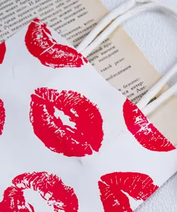 Nahaufnahme Detail der weißen Kosmetik Papiertragetasche mit rotem Lippenmuster und Griffen.