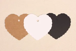Close-up detail of heart-shaped scalloped blank paper tags in kraft white and black.