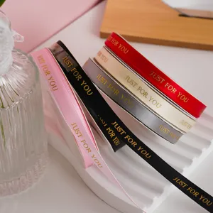Dettaglio di nastri decorativi multicolore con stampa dorata per confezioni regalo.